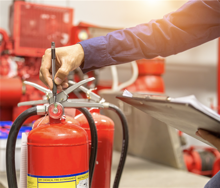 A hand pointing to a fire extinguisher.